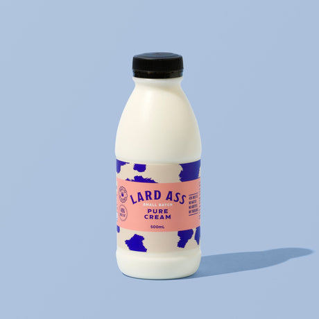 A 300ml bottle of Lard Ass Pure Cream against a solid light blue background. The bottle is white with a black cap and a pink and blue cow-print label.